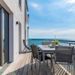 Terrasse mit Tisch und Stühlen bietet Meerblick. Holzdecke und Metallgeländer.