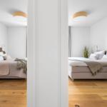 Zimmer mit Bett, Holzboden und Deckenleuchte