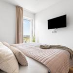 Schlafzimmer mit Bett, TV und Balkonansicht.