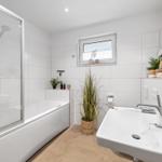Badezimmer mit Badewanne, Dusche, Waschbecken und Pflanzen.