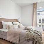 Schlafzimmer mit Bett, Fenster und Pflanze.