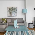 Ein Wohnzimmer mit grauem Sofa, blauem Couchtisch und Kaminofen.