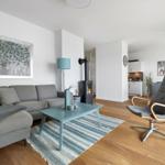 Wohnzimmer mit Sofa, Kamin und Sessel auf Holzboden.