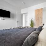 Schlafzimmer mit Bett, Fernseher an der Wand und Spiegel.