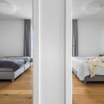 Zwei Schlafzimmer mit Betten, Holzboden und Fenstern mit Vorhängen.