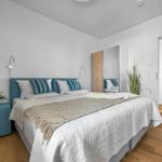 Schlafzimmer mit Bett, Nachttisch, Spiegel und Pflanzen.