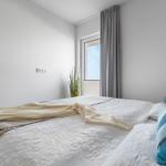 Schlafzimmer mit Bett, blauen Kissen und Fenster mit grauen Vorhängen.