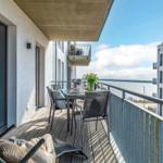 Terrasse mit Tisch, Stühlen und Meerblick. Holzdielen und Metallgeländer.