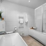 Bathroom with bathtub, shower, and towel rack.