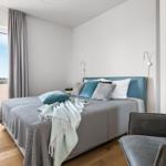 Bedroom with bed, armchair, and view of water through window.