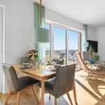 Dining area with table and chairs, view to balcony and living room with seating.