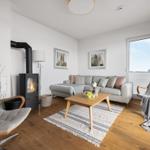 Wohnzimmer mit Sofa, Kamin und zwei Sesseln auf Holzboden.