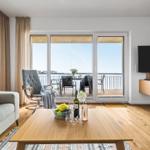 Wohnzimmer mit Balkonblick, Sofa, Fernseher und Holzboden.