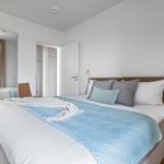 Schlafzimmer mit Bett, Nachttisch, Spiegel und Holzboden.