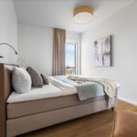 Schlafzimmer mit Bett, Fenster und Wandbild.