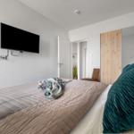 Schlafzimmer mit Bett, Fernseher und Spiegelschrank