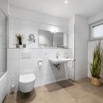 Badezimmer mit Dusche, Waschbecken, Toilette und Waschmaschine.