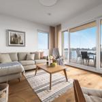 Wohnzimmer mit Sofa, Couchtisch und Balkon mit Meerblick.