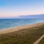 Strand mit Dünen und Weg entlang des Meeres bei Sonnenuntergang.