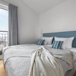 Schlafzimmer mit Bett, Fenster und Balkonblick.