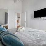 Schlafzimmer mit Bett, Fernseher und Blick in die Küche.