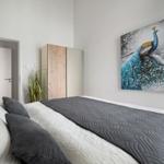 Schlafzimmer mit Bett, Kleiderschrank und Wandbild eines Pfauens.