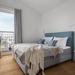 Schlafzimmer mit Bett, Fenster und Balkon. Wandmontierte TV und Pflanzen.