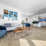 Wohnbereich mit Sofa, Sessel und Küchenbereich mit Arbeitsplatte