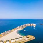 Strand und Hafen mit Häusern und Segelbooten im klaren Blauen Meer.