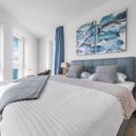 Schlafzimmer mit Blick aufs Meer, blauem Vorhang und Fischbildern an der Wand.