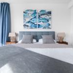 Schlafzimmer mit Bett, Fenster und Wandbildern mit Fischen.