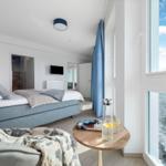 Schlafzimmer mit Blick aufs Meer. Bett, Tisch und Fenster sind sichtbar.