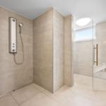 Dusche mit Duschbrause und Glaswand. Sauna mit Sitzbank und Fenster.
