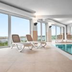 Indoorpool mit Liegestühlen und Blick auf Wasser