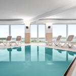 Innenpool mit Liegestühlen und Blick auf Wasser