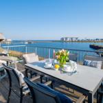 Terrasse mit Tisch, Stühlen und Blick auf Wasser und Ufer.