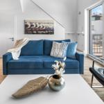 Blauer Sofa mit Kissen und Decke im Wohnzimmer mit Blick auf Balkon.