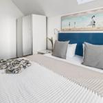 Schlafzimmer mit Bett, blauem Kopfteil und Blick auf Balkon.