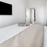 Schlafzimmer mit Bett, Fernseher und Blick in einen angrenzenden Raum.