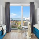 Zwei Betten mit Blick aufs Meer und Balkon mit Stuhl.