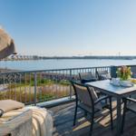 Terrasse mit Tisch, Stühlen und Meerblick. Grill und Sonnenschirm sind vorhanden.