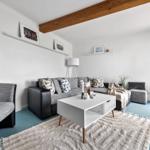 Wohnzimmer mit grauem Sofa, weißem Tisch und blauem Boden.