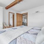 Schlafzimmer mit Bett, Kleiderschrank und Blick in angrenzende Räume.