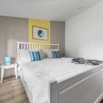 Schlafzimmer mit weißem Bett, blauen Kissen und Holzboden.