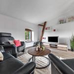 Wohnzimmer mit Ledersofa, Fernseher und Holzbalken.