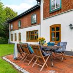 Terrasse mit Tisch und Stühlen vor einem Haus mit weißer und roter Ziegelwand.