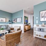 Wohnzimmer mit Sofa, Rattanmöbeln und Wandbildern an blauen Wänden.