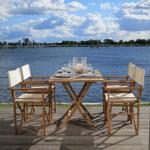 Holztisch mit Stühlen auf Terrasse mit Blick auf Wasser und Himmel.