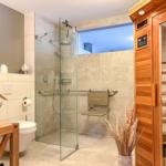 Bad mit Dusche, Toilette und Sauna. Glaswand, Holzverkleidung und Dekoration.