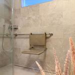 Duschbereich mit Sitzbank und Handlauf an der Wand